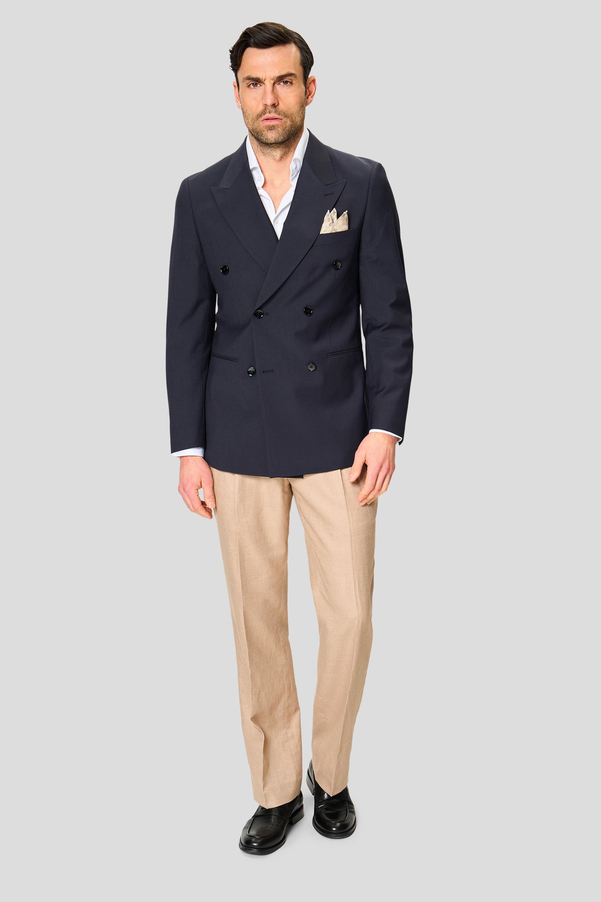 Mand i mørkeblå dobbeltradet blazer med beige bukser og hvid skjorte